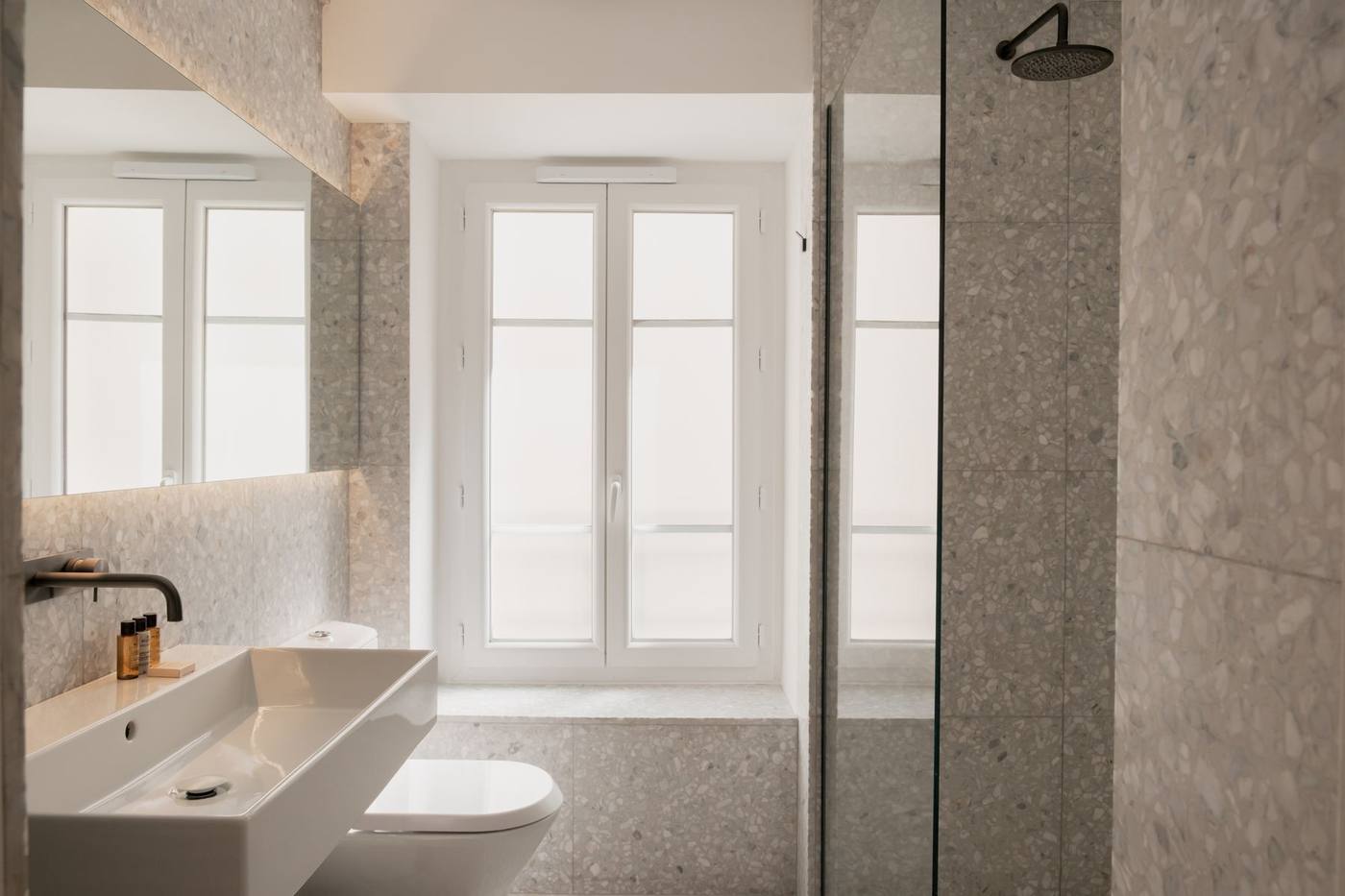 Salle d'eau en terrazzo éclairée par sa propre fenêtre